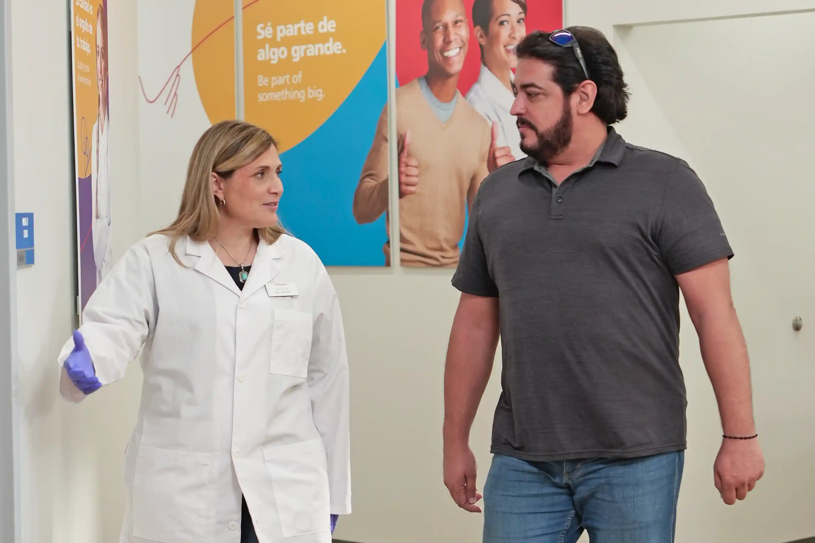 Un donante y una profesional de la salud conversan mientras caminan por un pasillo.