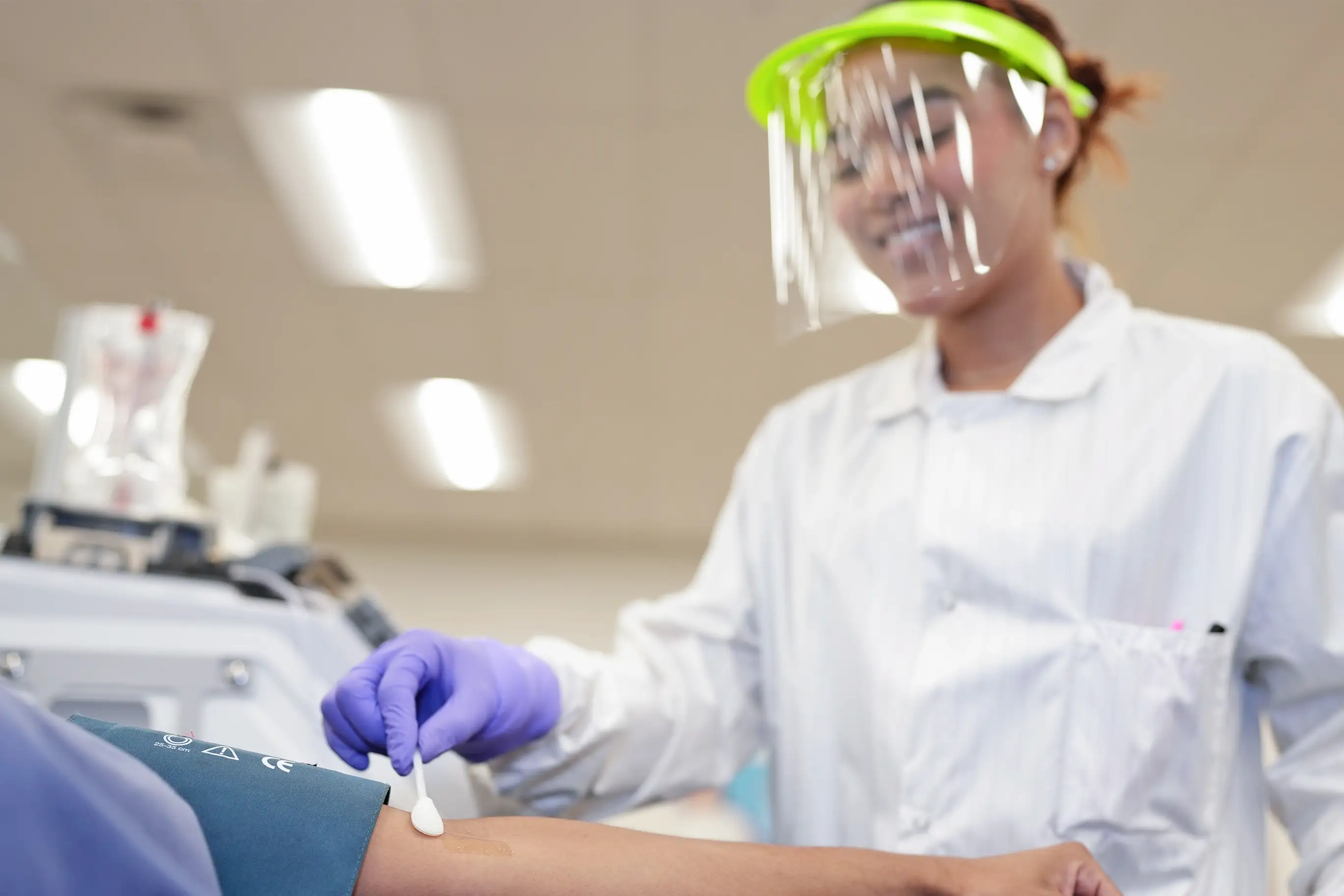 Una profesional de la salud le desinfecta el brazo a una donante antes de donar plasma.