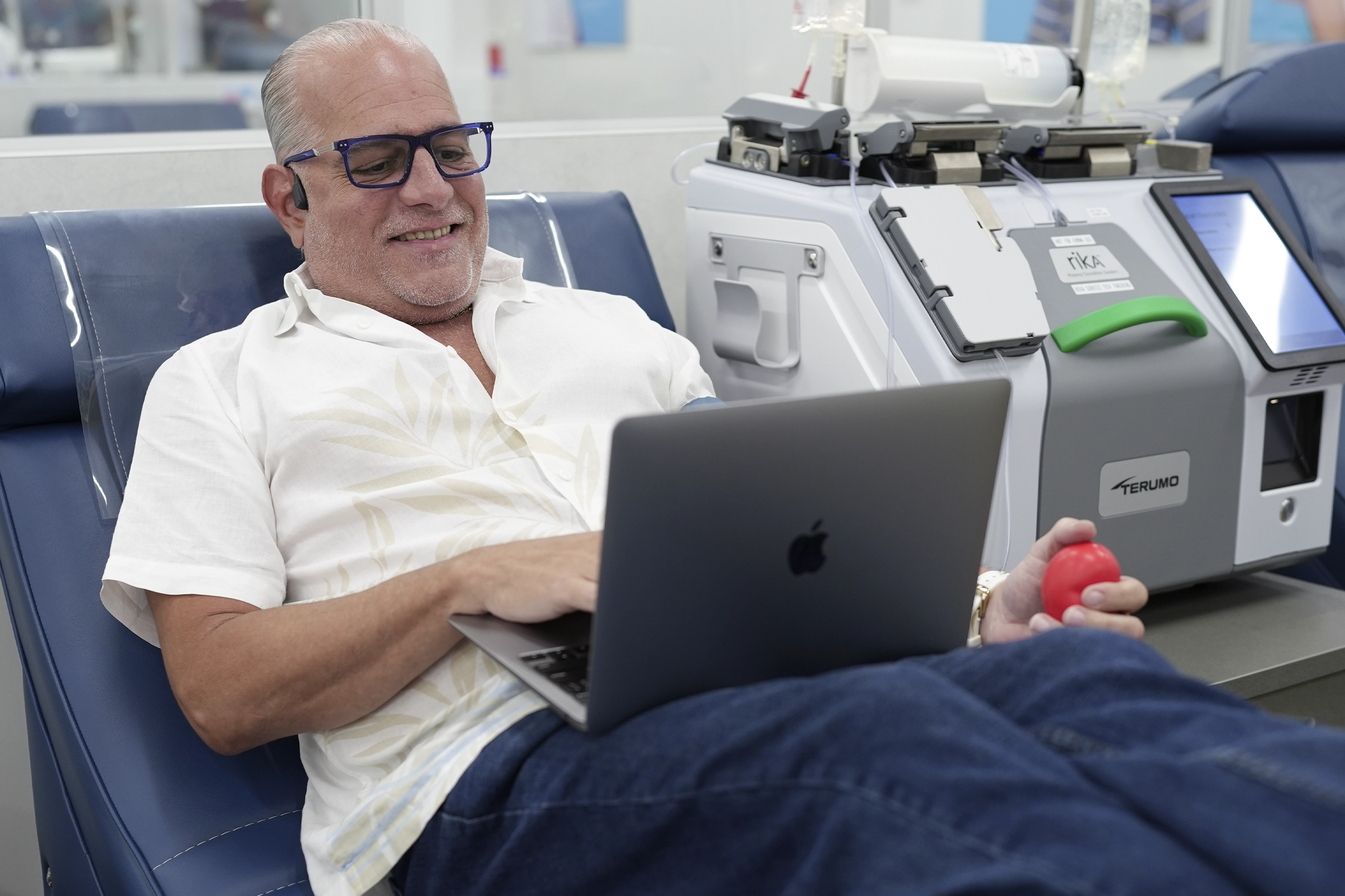 Hombre dona plasma mientras usa su computadora y se entretiene durante el proceso